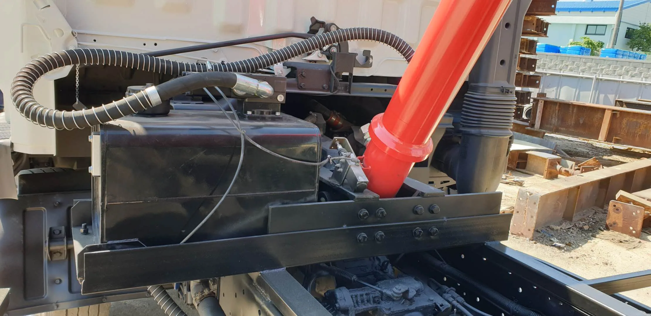Front-end telescopic cylinder installed under a tipper body, with the red stage extended